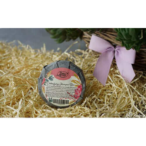 Natural shampoo bar for greasy hair, featuring floral packaging on straw background for healthy scalp.