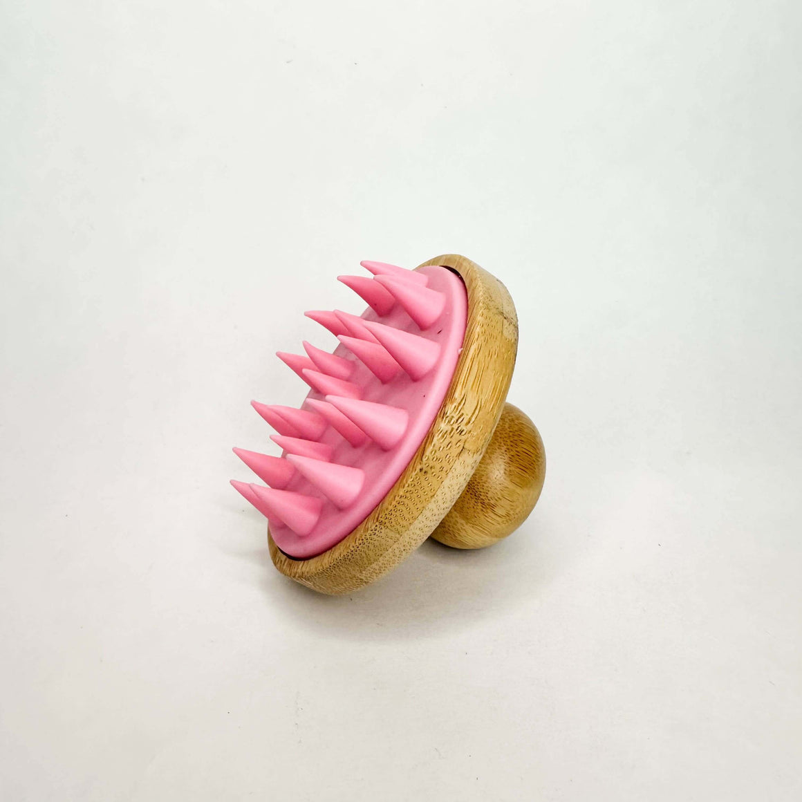 Pink silicone scrubber with wooden handle on a white background