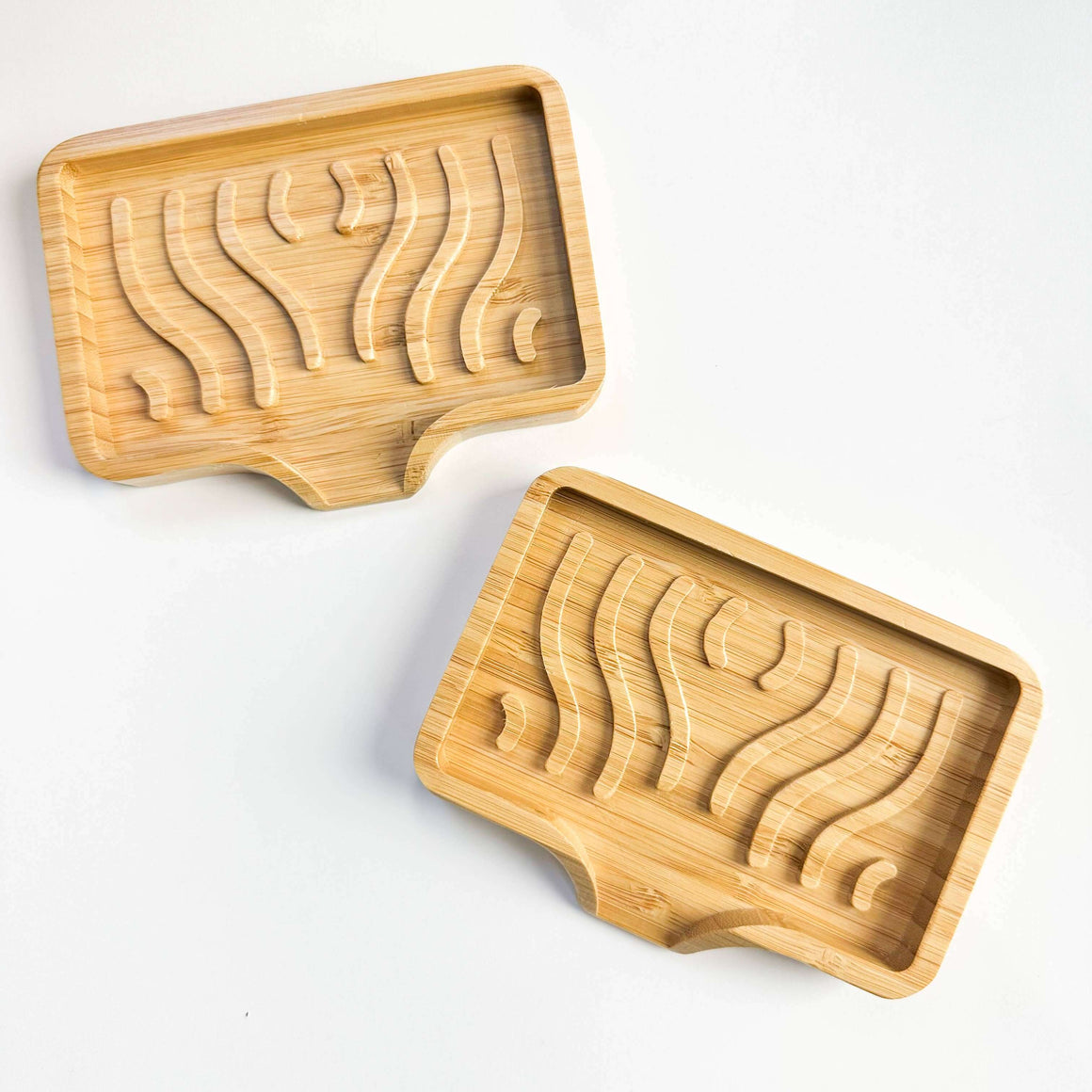 Two wooden soap molds with wavy patterns on a white background