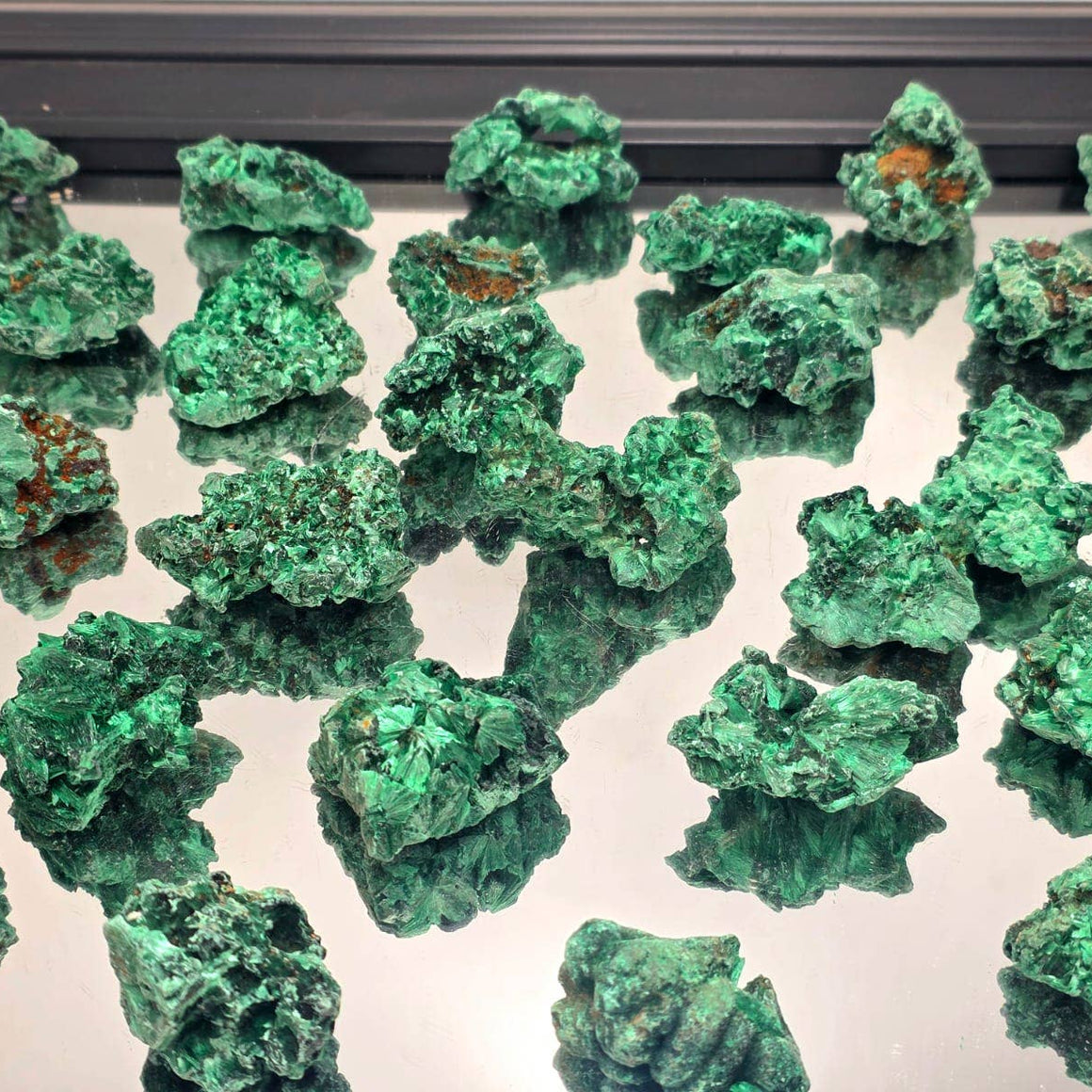 Collection of green mineral specimens on a reflective surface