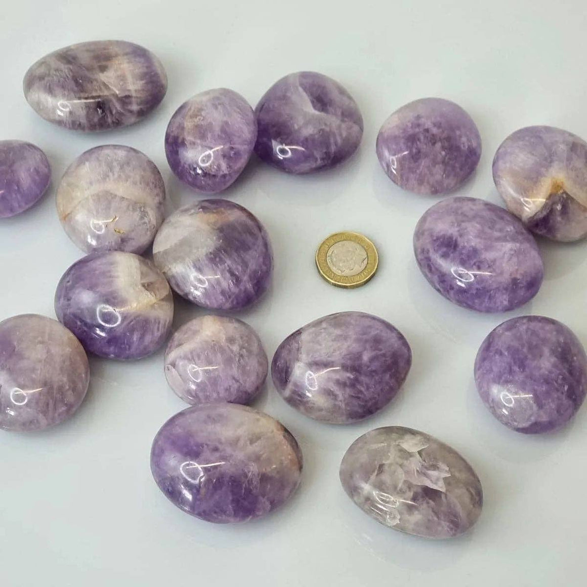Purple marbled stones with a coin for scale on a white background