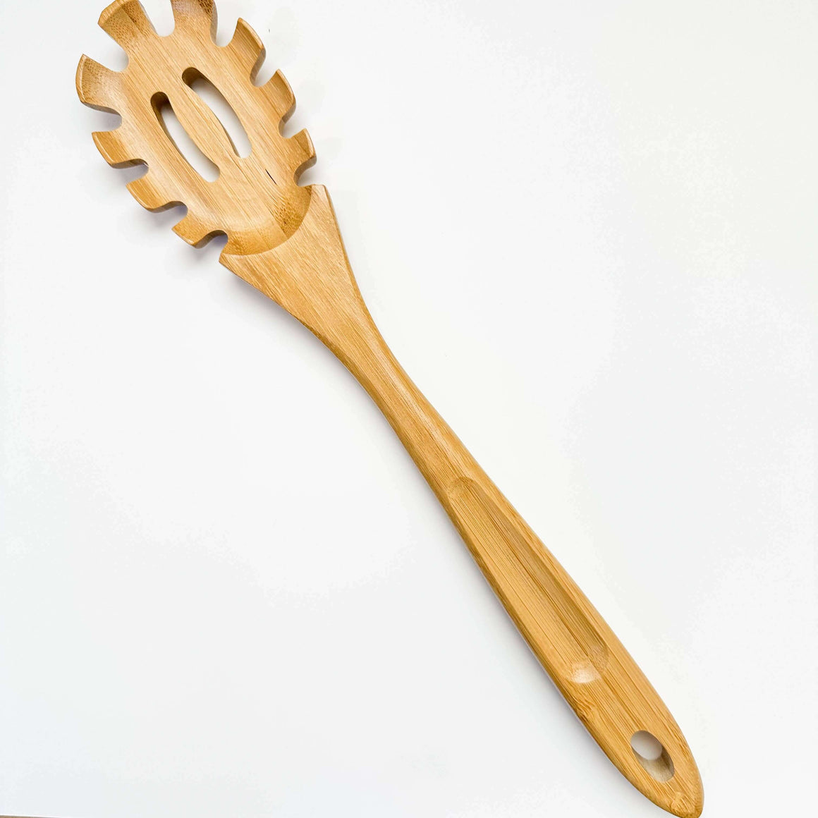 Wooden spaghetti server on a white background