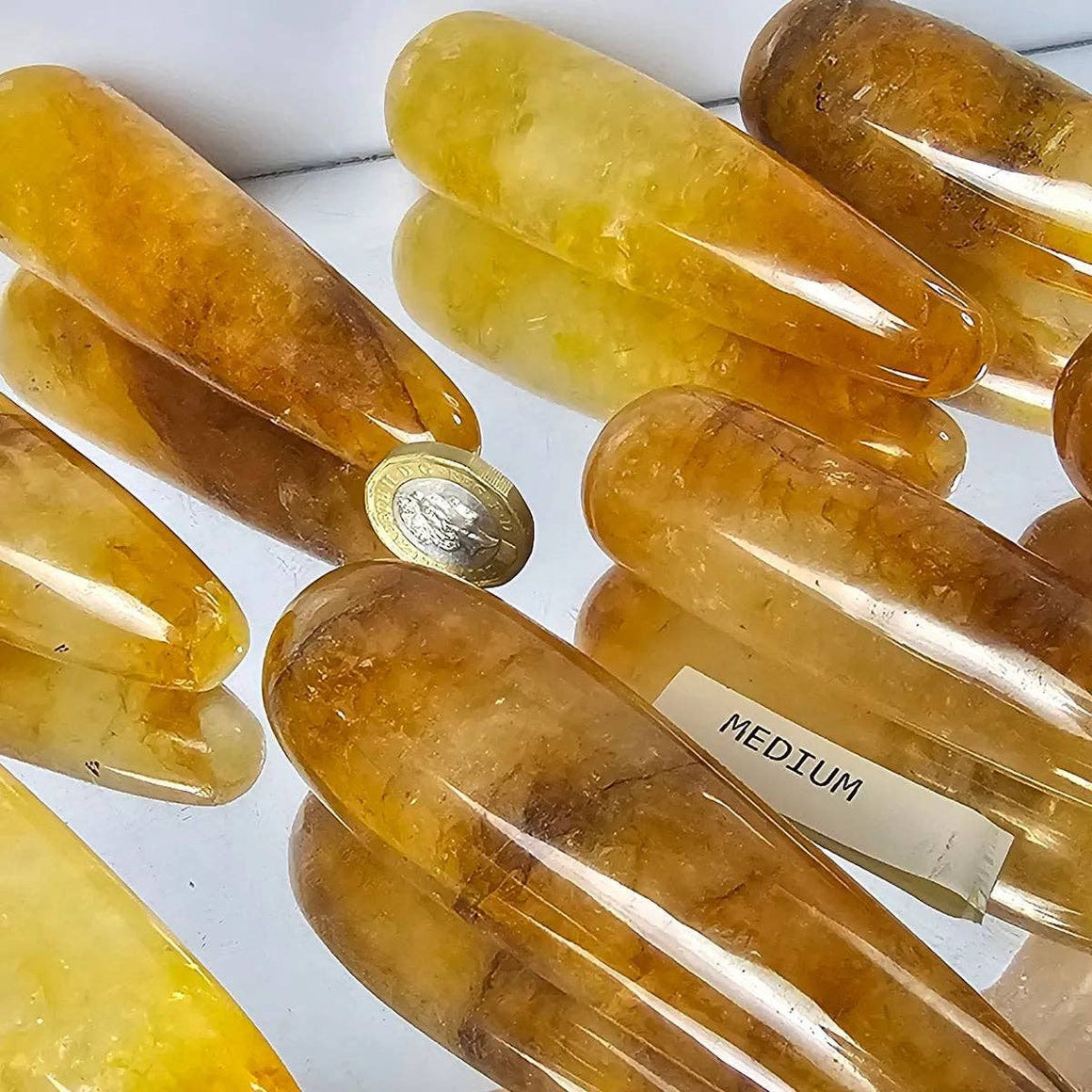 Yellow crystal objects with a coin and label on a reflective surface