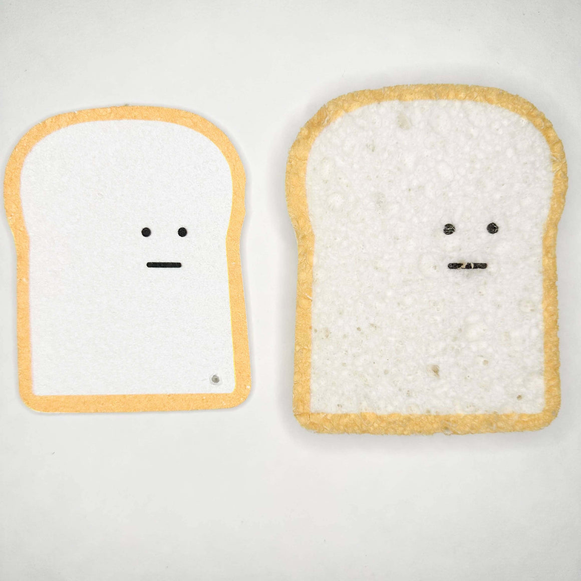 Two pieces of bread with faces drawn on a white background