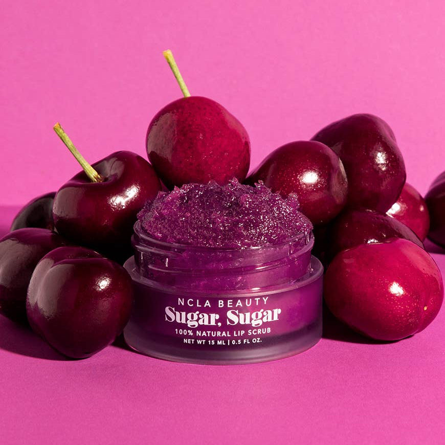 Purple lip scrub jar with cherries on a pink background