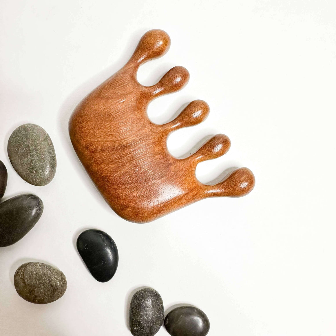 Wooden hand-shaped tool with stones on a white background