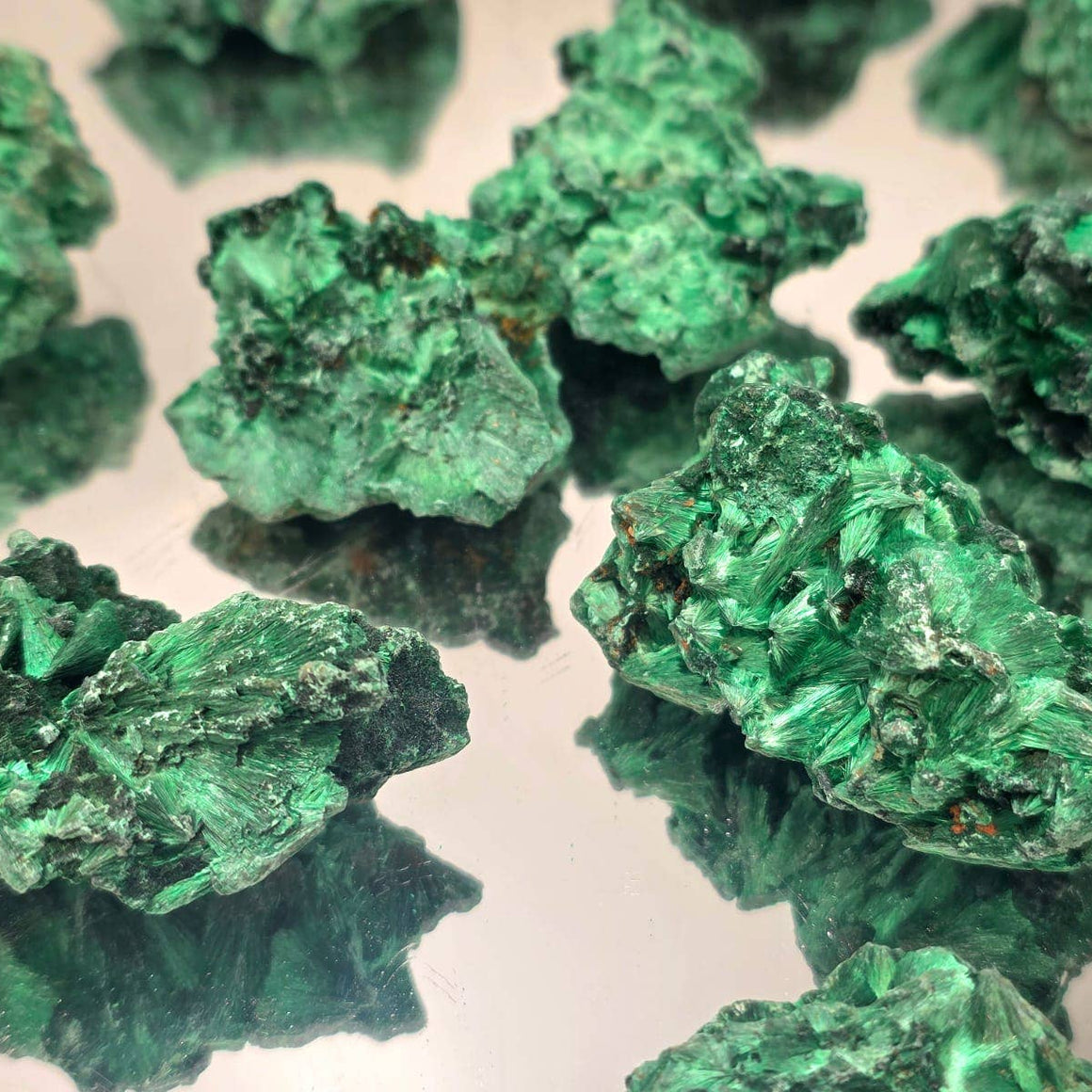 Close-up of green mineral crystals on a reflective surface