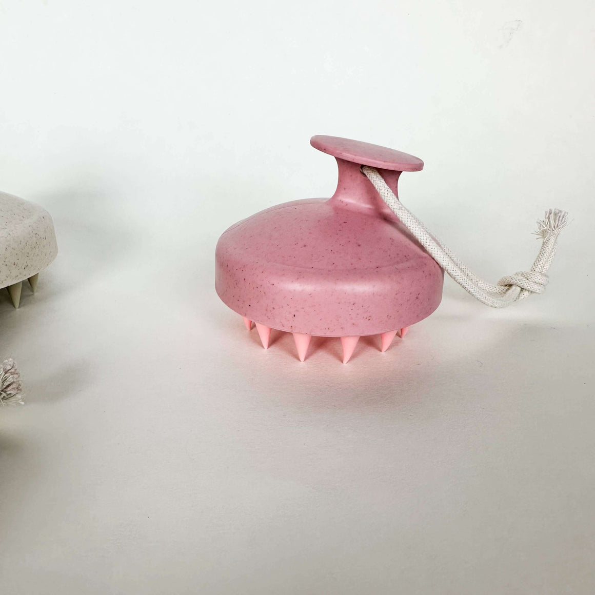 Pink scalp massager with a rope on a white background