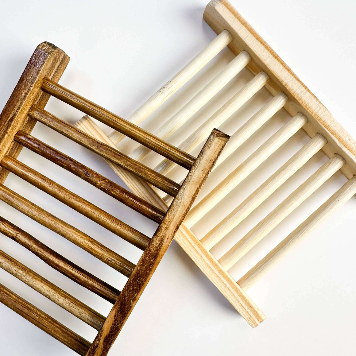 Two wooden soap dishes, one brown and one beige, on a white background.