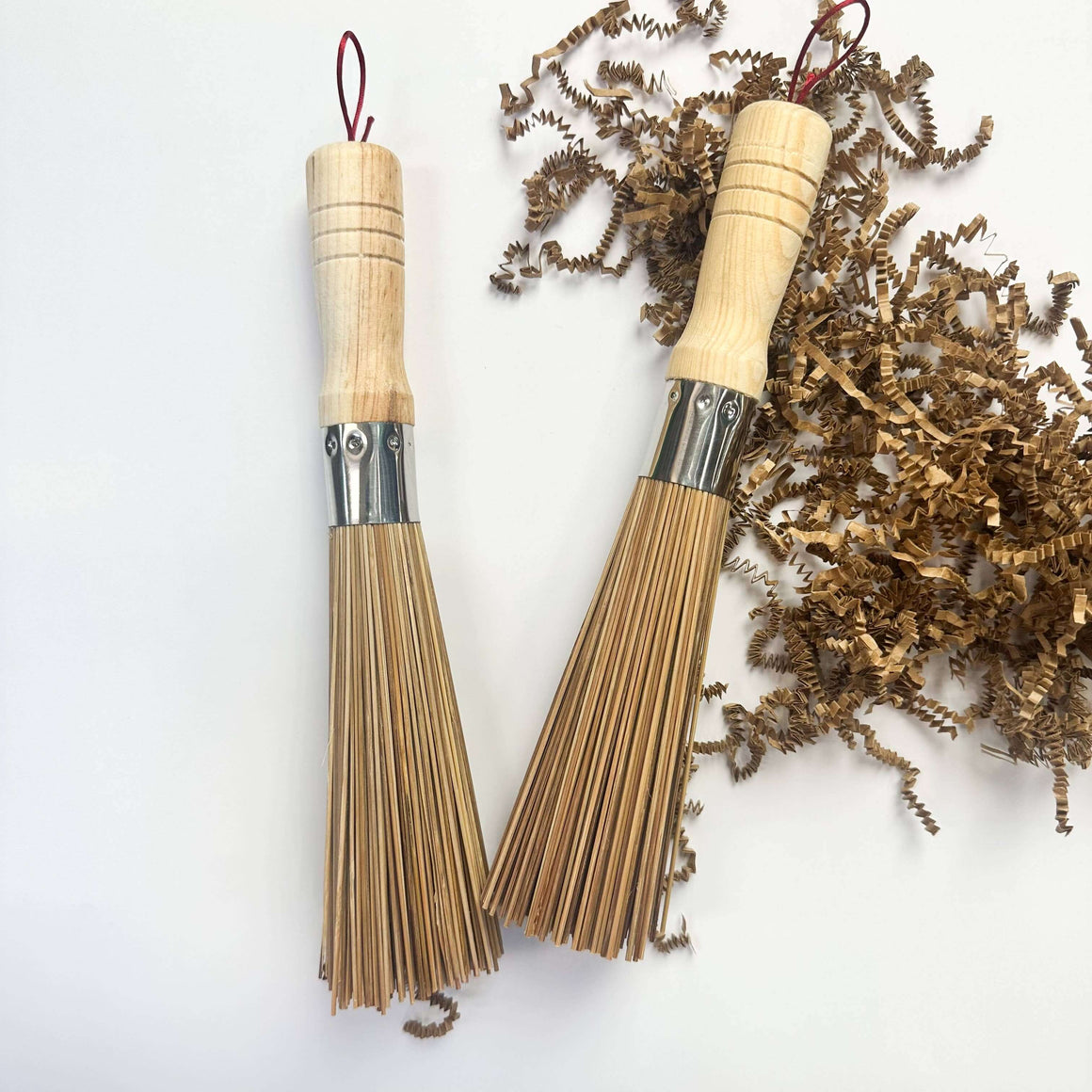 Two wooden brooms with metal heads on a white background