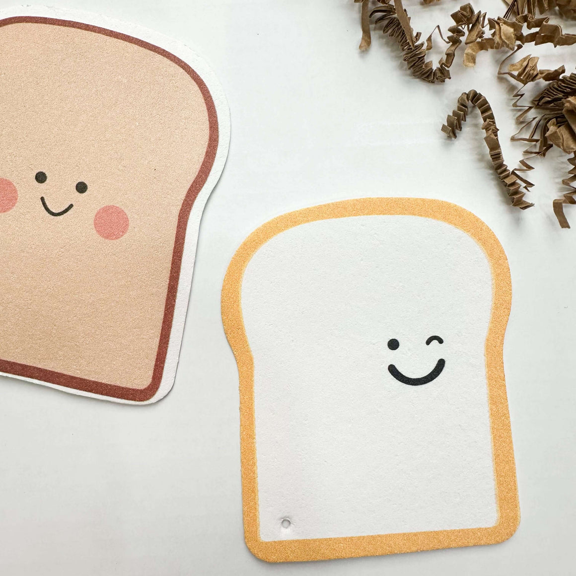 Two cute toast-shaped cushions with smiley faces on a light background