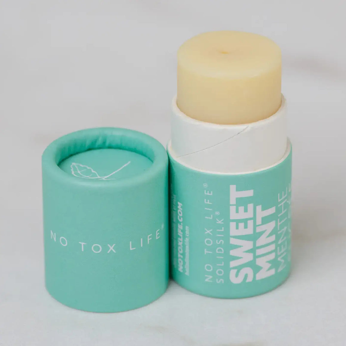 Solid mint flavor product with green container on a light gray background