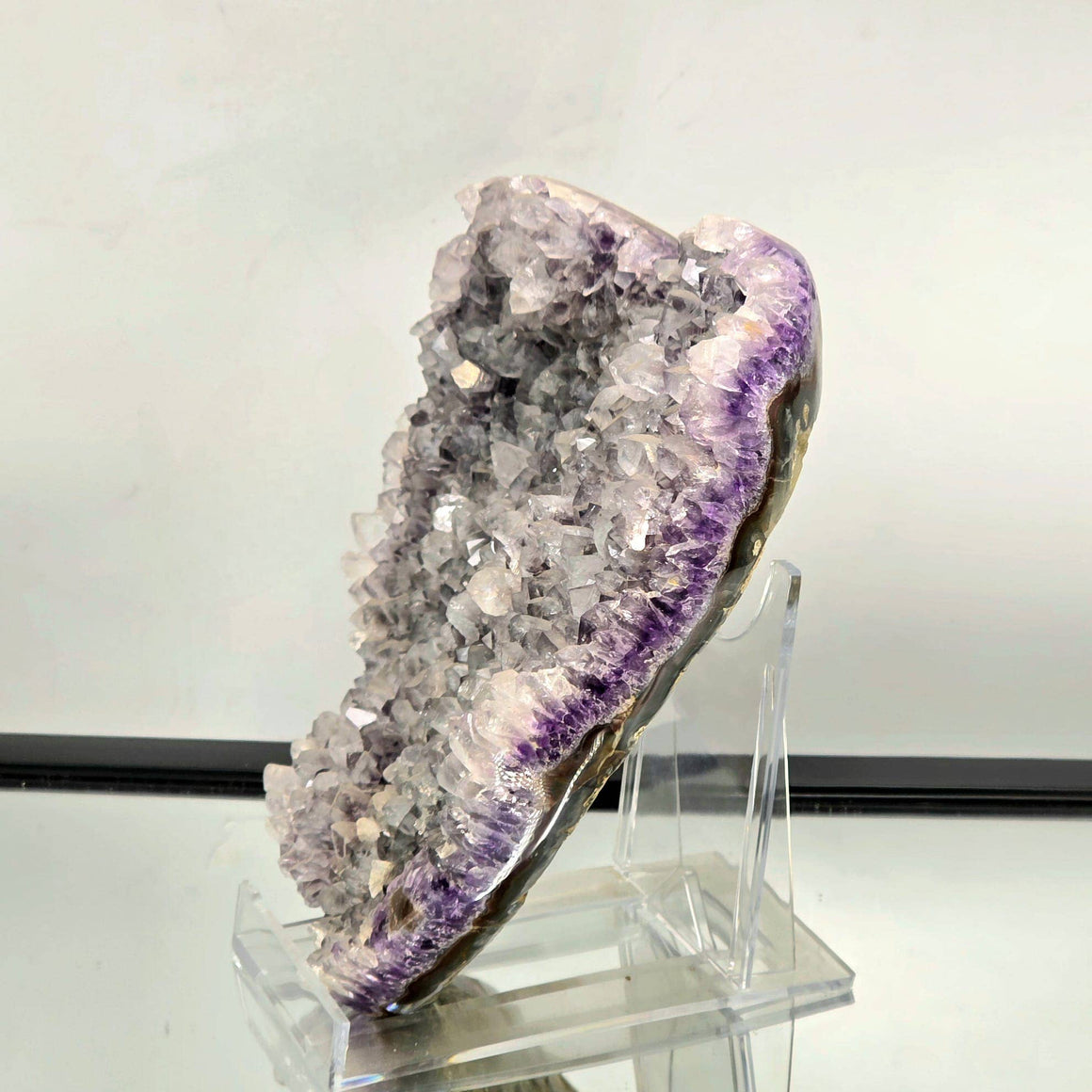 Amethyst crystal on a stand against a neutral background