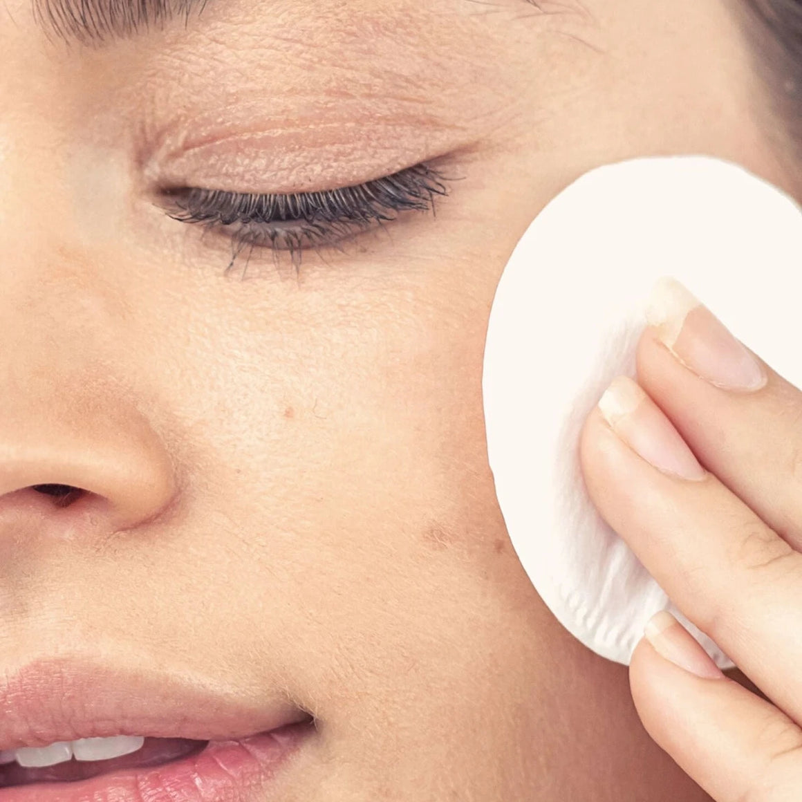 Person using a white cotton pad on their face