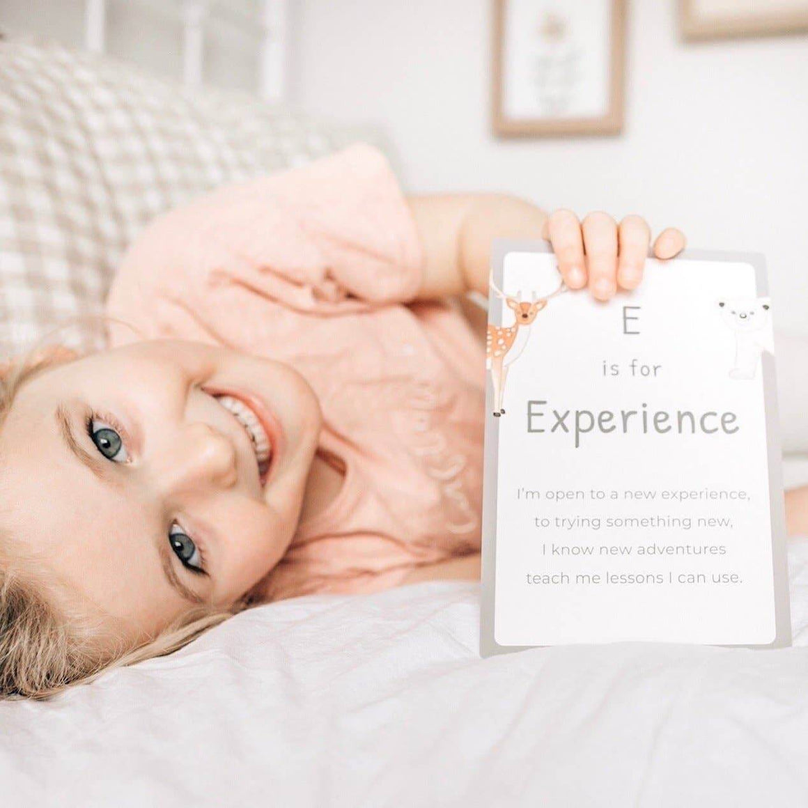 Child lying on a bed with a card reading 'E is for Experience' held above them.