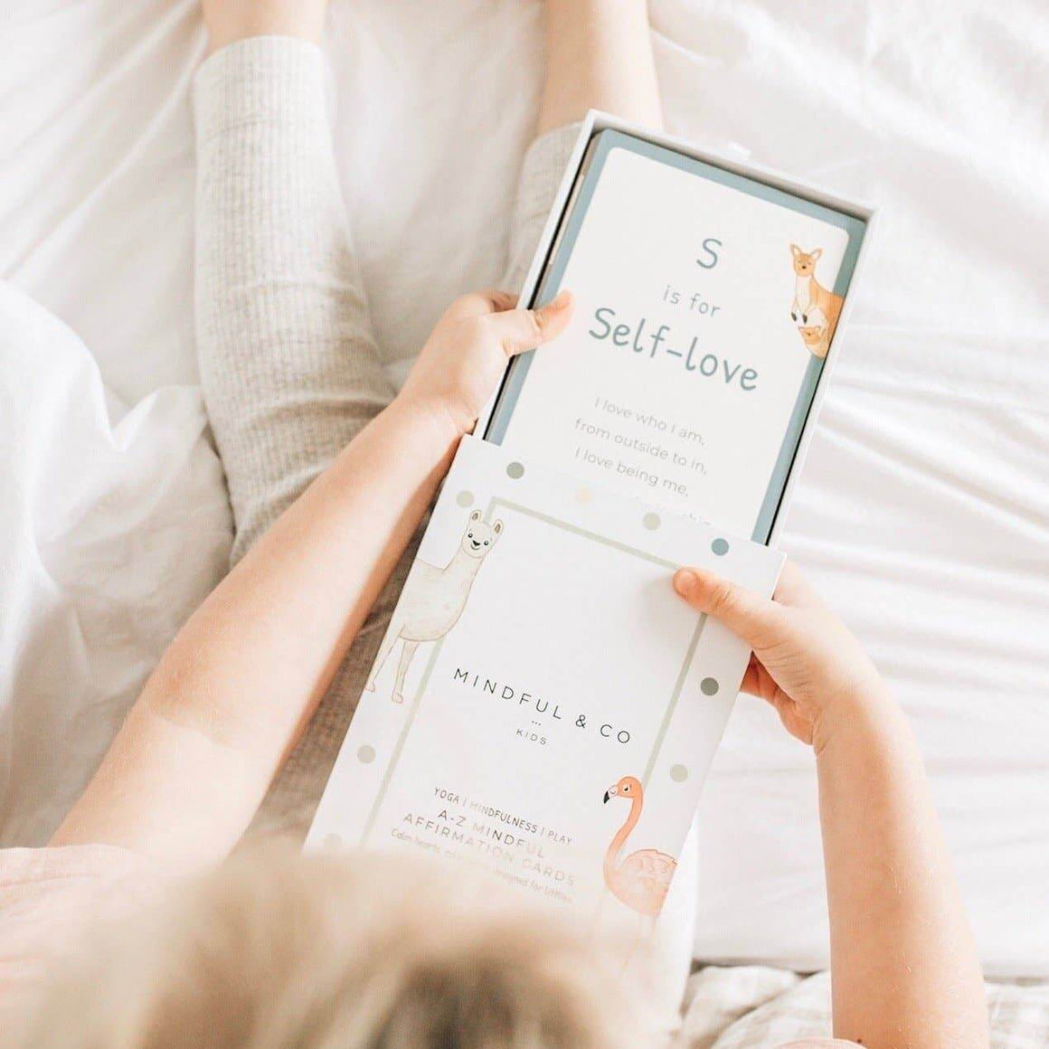 Person holding a product packaging with 'S is for Self-love' text and 'Mindful & Co' branding.