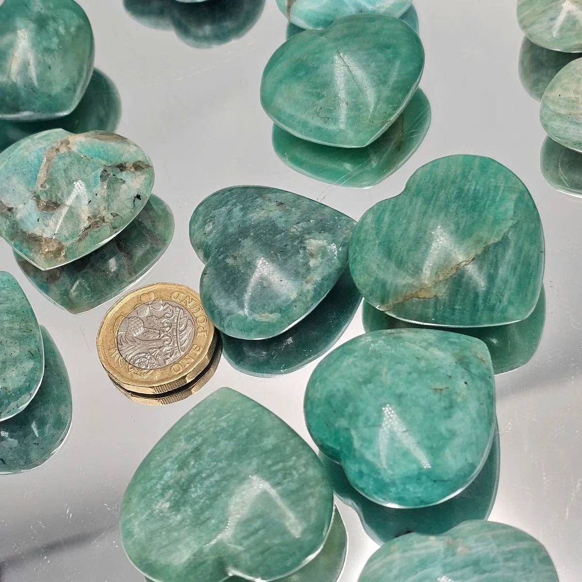 Green stones on a reflective surface with a coin for scale