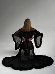 Back view of a woman wearing a BURLESQUE Soft Mesh Dress with dramatic sleeves and a flowing train.