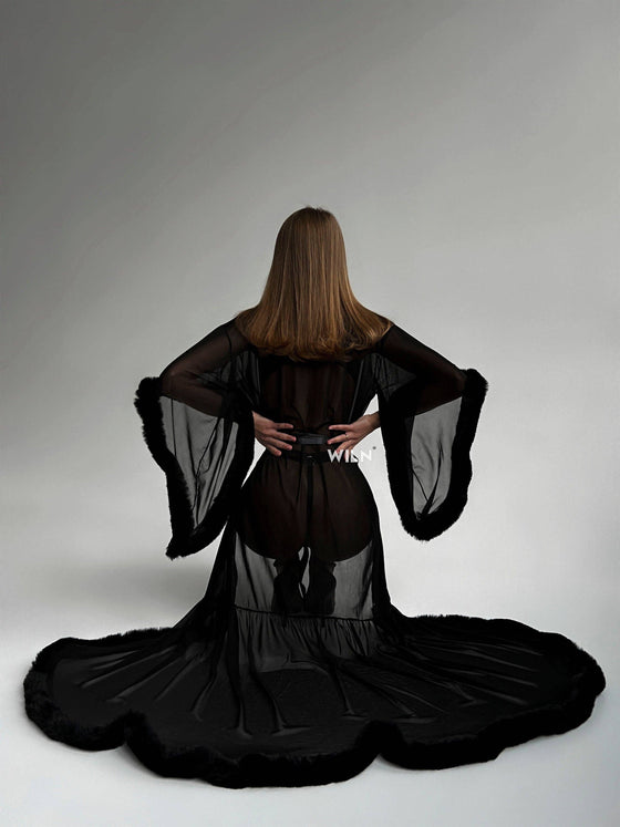Back view of a woman wearing a BURLESQUE Soft Mesh Dress with dramatic sleeves and a flowing train.