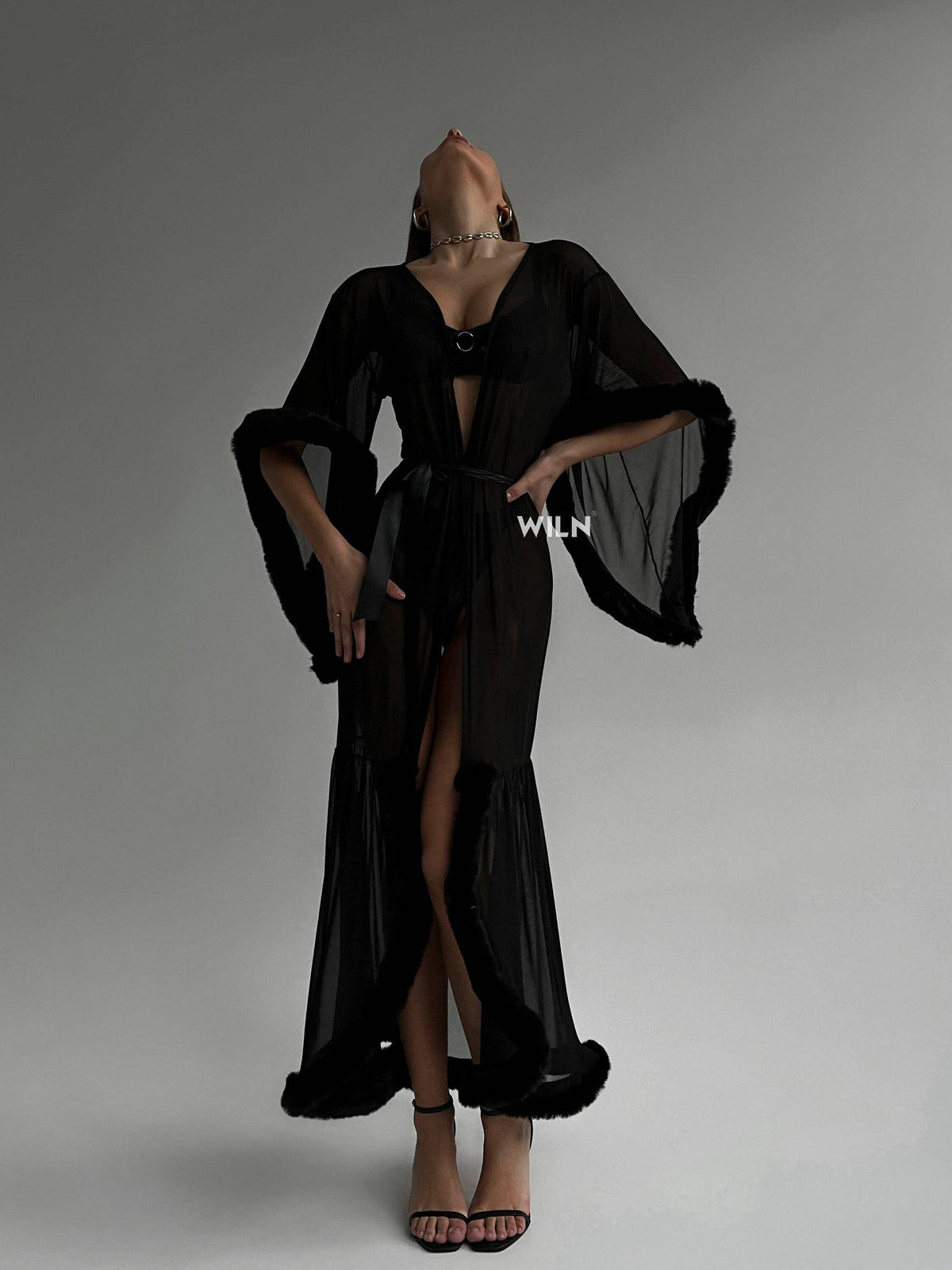 Model wearing BURLESQUE Soft Mesh Dress with dramatic sleeves and a high slit, showcasing elegance and confidence.