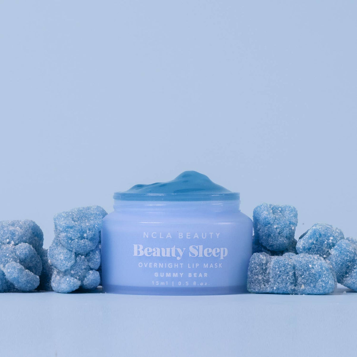 Blue lip mask jar with gummy bear-shaped candies on a light blue background