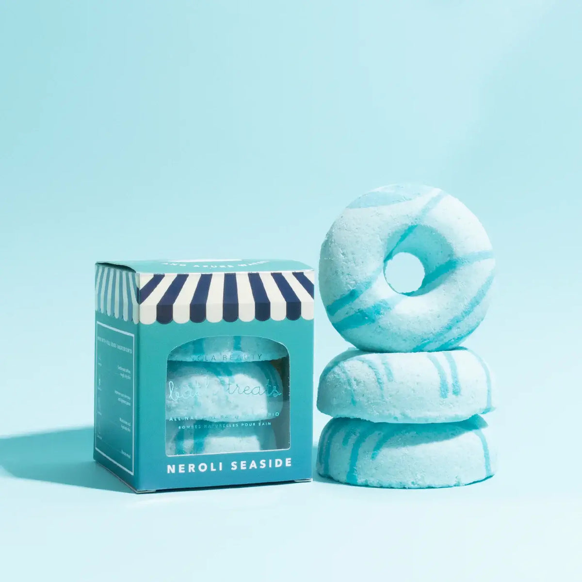 Stack of blue striped bath bombs with a packaging box on a light blue background