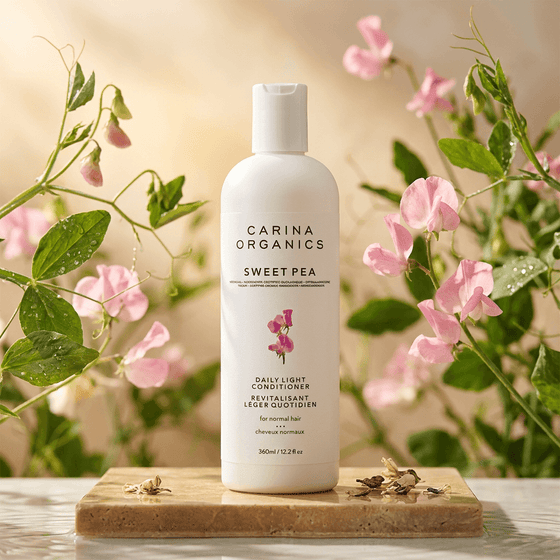 Carina Organics Sweet Pea skincare product on a wooden board with flowers in the background