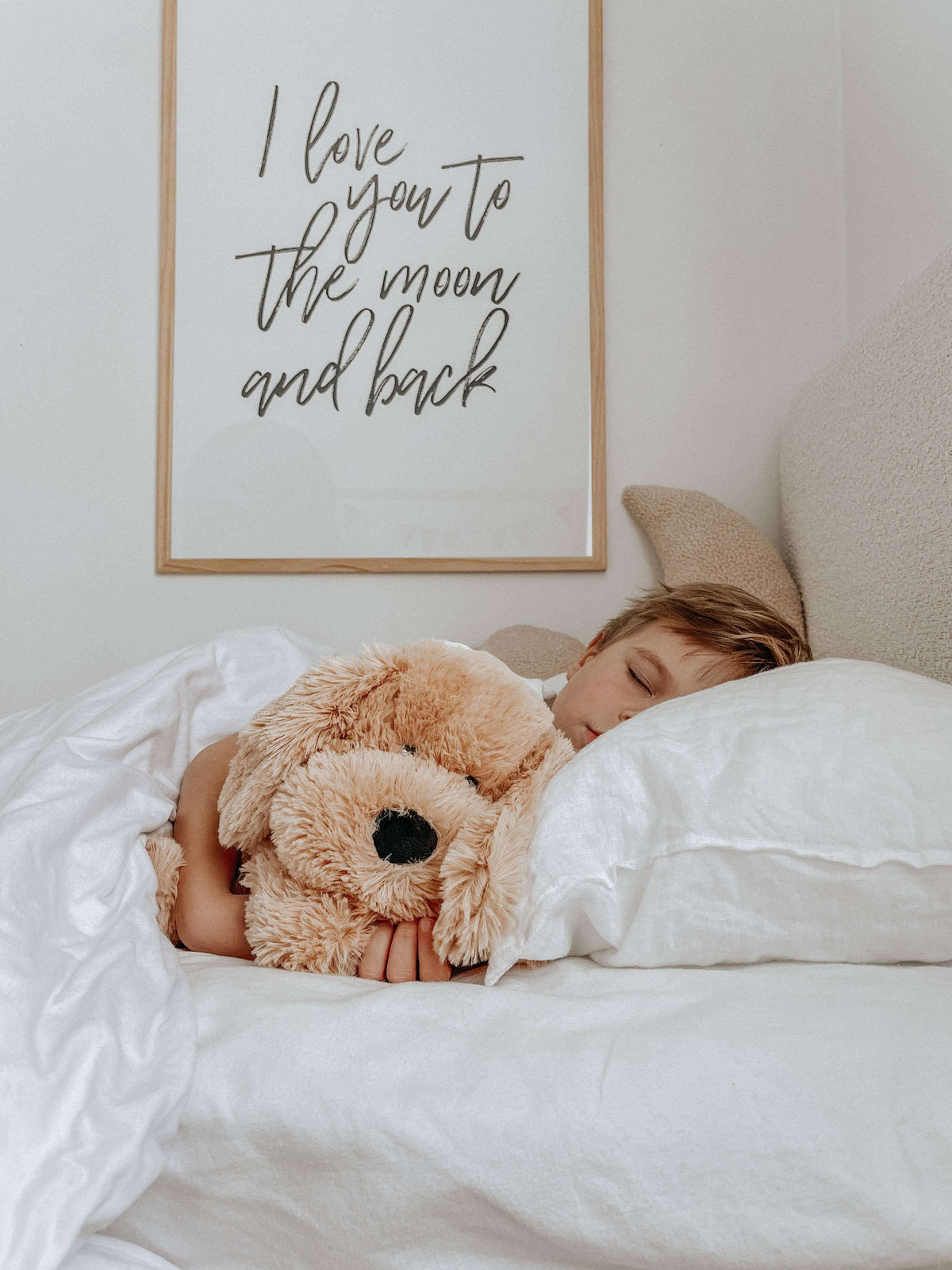 Child sleeping peacefully with Charlie The Weighted Puppy Dog Teddy in bed for comfort and support.