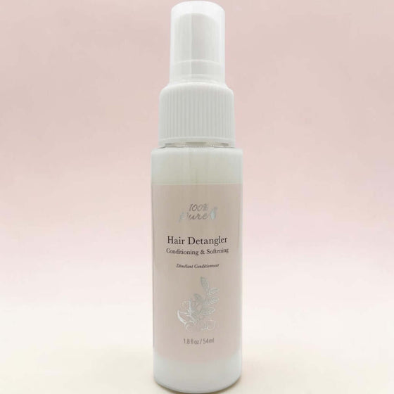 Hair detangler spray bottle on a light pink background