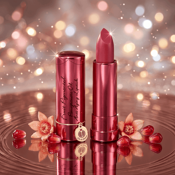 Dark Pink lipstick and case with flowers on a reflective surface and bokeh background
