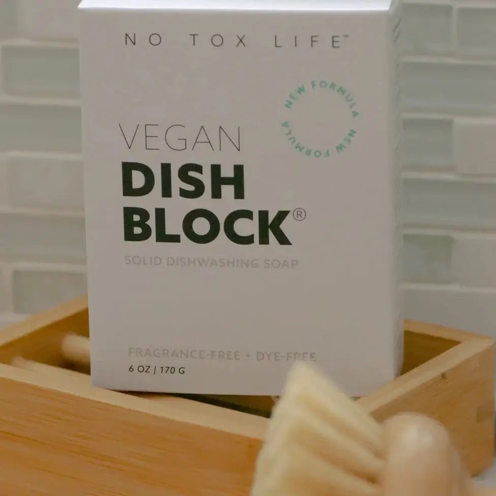 Vegan dish block solid dishwashing soap packaging on a wooden tray with a blurred background