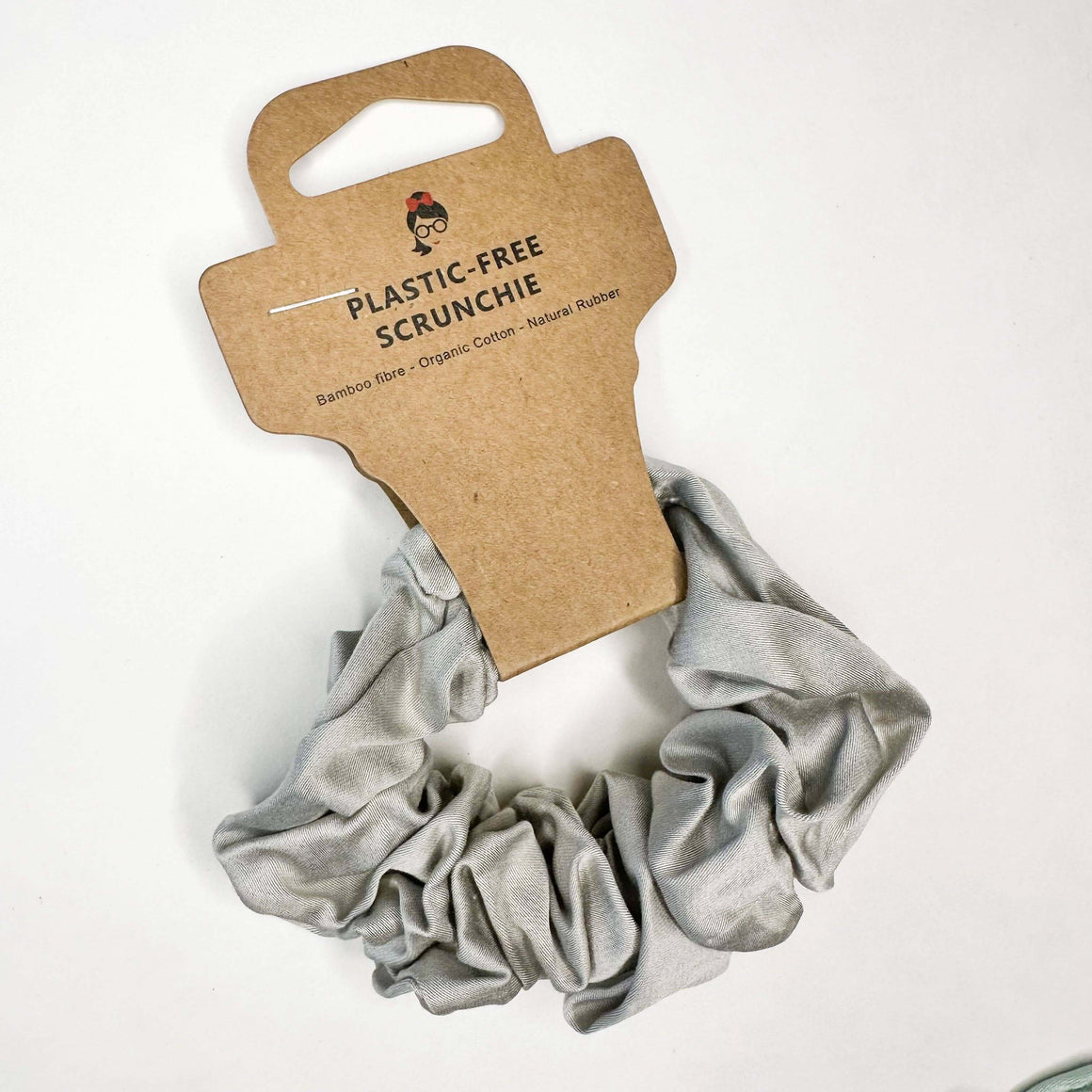 Gray scrunchie on a cardboard holder with 'Plastic-Free Scrunchie' text on a white background