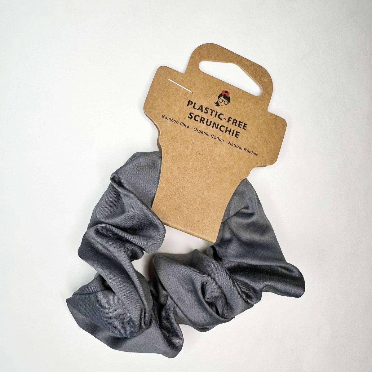Gray scrunchie on a white background with a cardboard holder labeled 'Plastic-Free Scrunchie'.