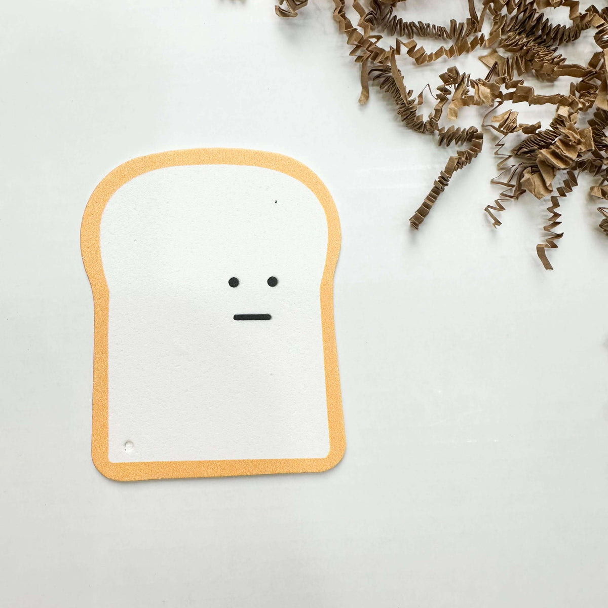 Toy resembling a piece of bread with a face on a white background