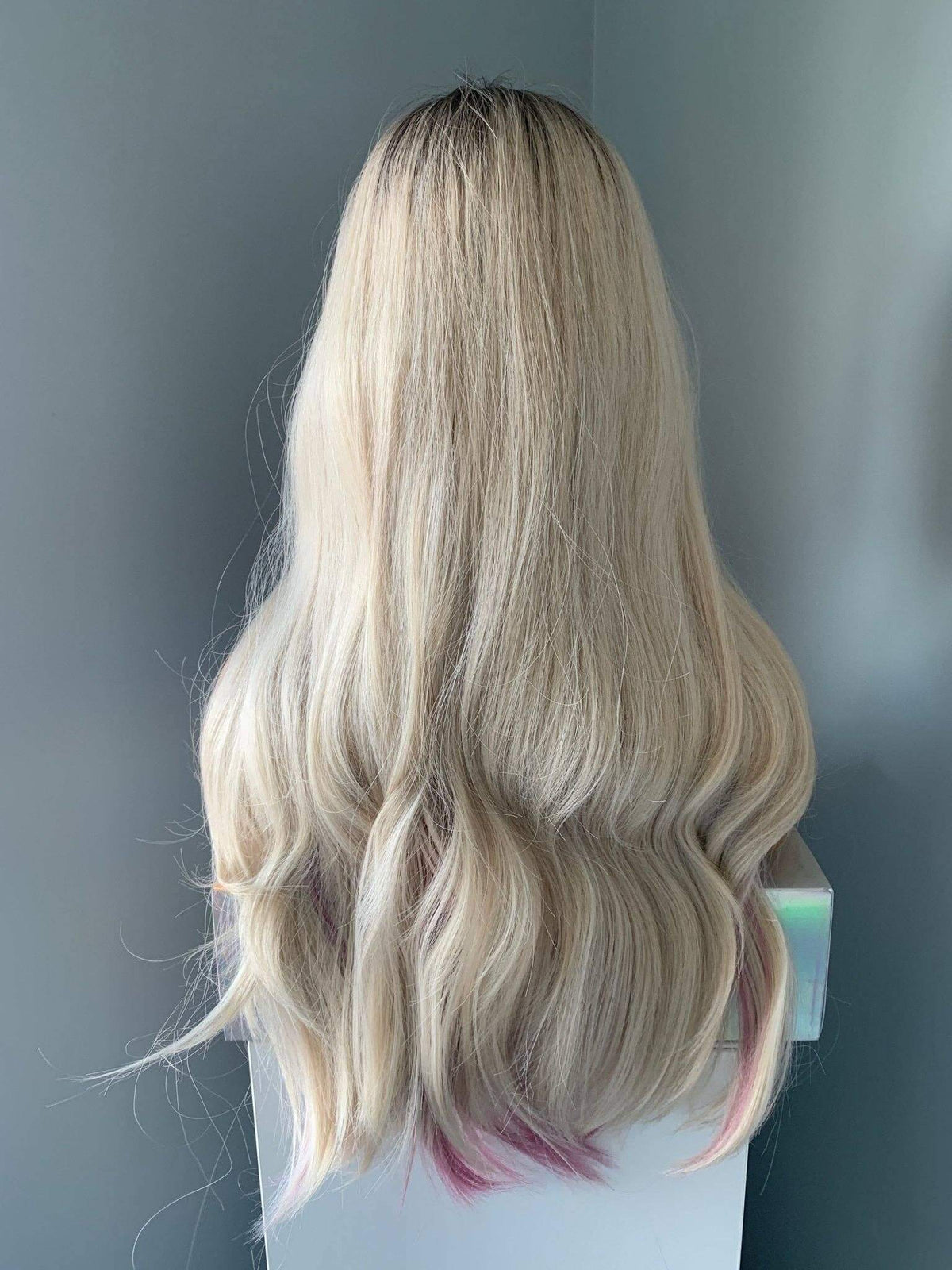 Blonde wig on a mannequin head against a neutral background