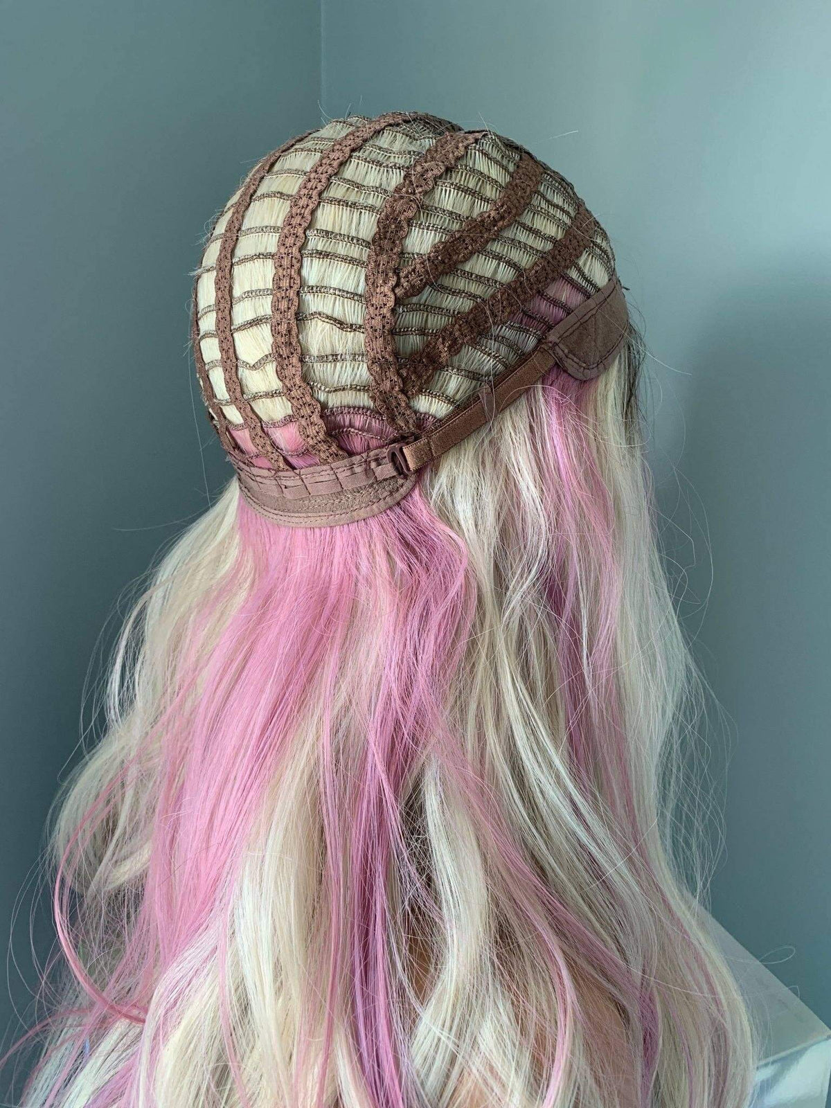 Head with pink and white hair styled in an intricate manner against a plain background