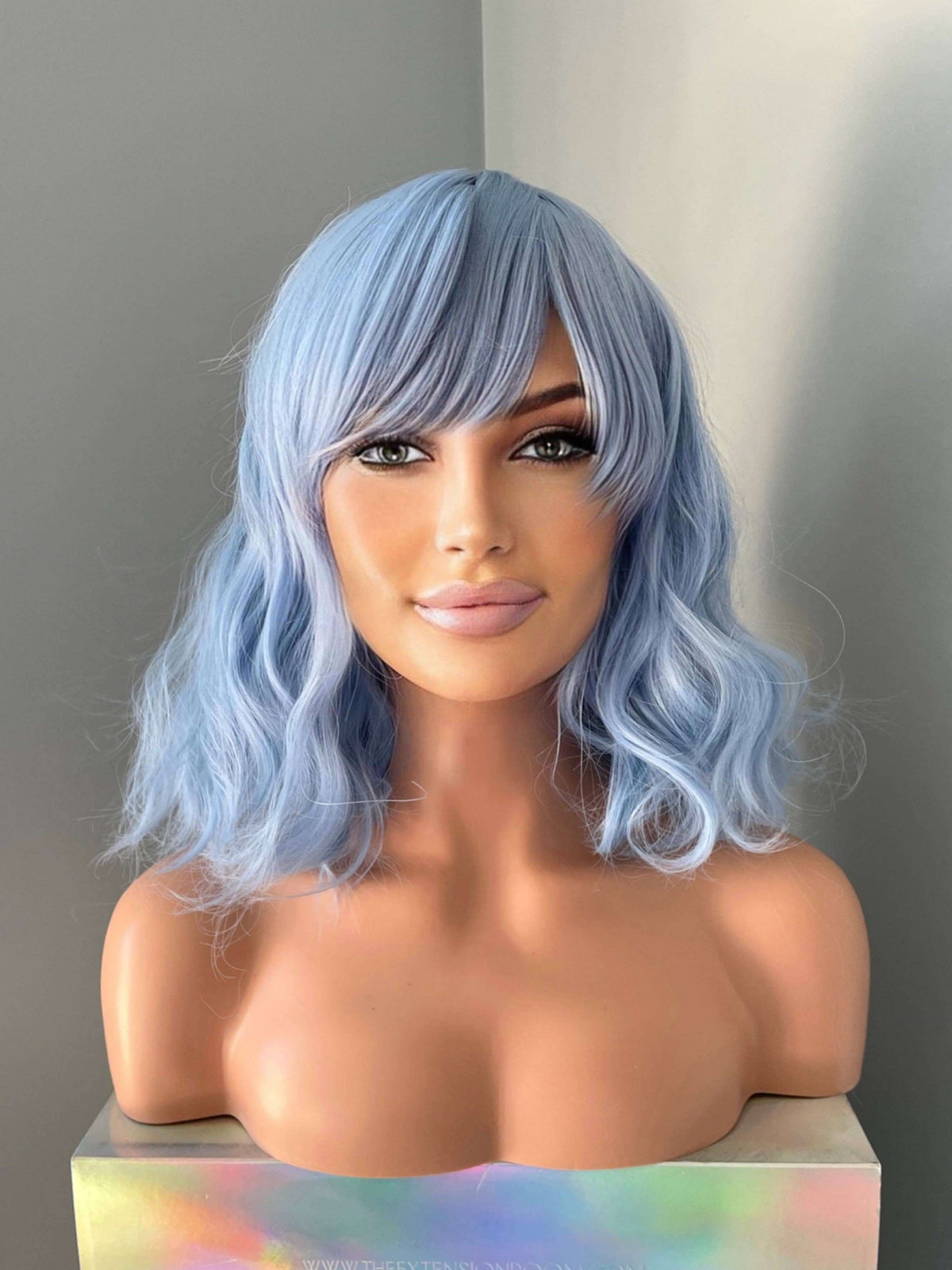 Faye Short Pastel Blue Body Wave Wig with Bangs displayed on a mannequin, showcasing soft waves and wispy bangs.