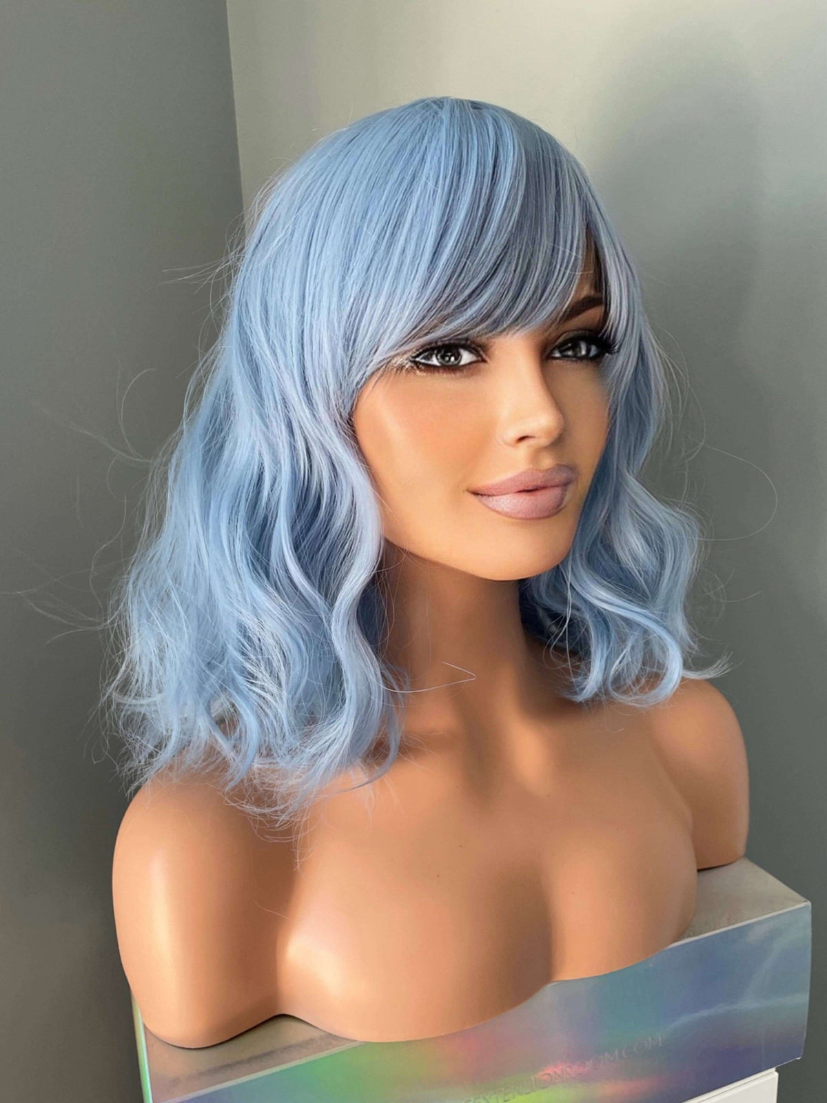 Faye Short Pastel Blue Body Wave Wig with Bangs displayed on a mannequin, showcasing soft waves and wispy bangs.