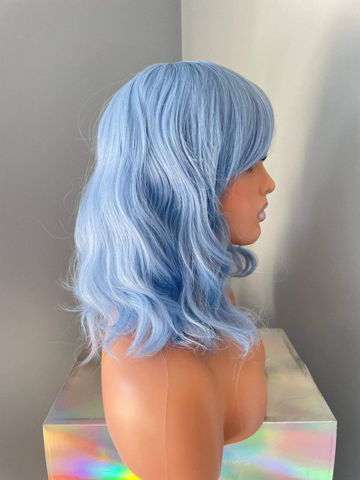 Faye Short Pastel Blue Body Wave Wig with Bangs displayed on a mannequin side view, showcasing soft waves and wispy bangs.