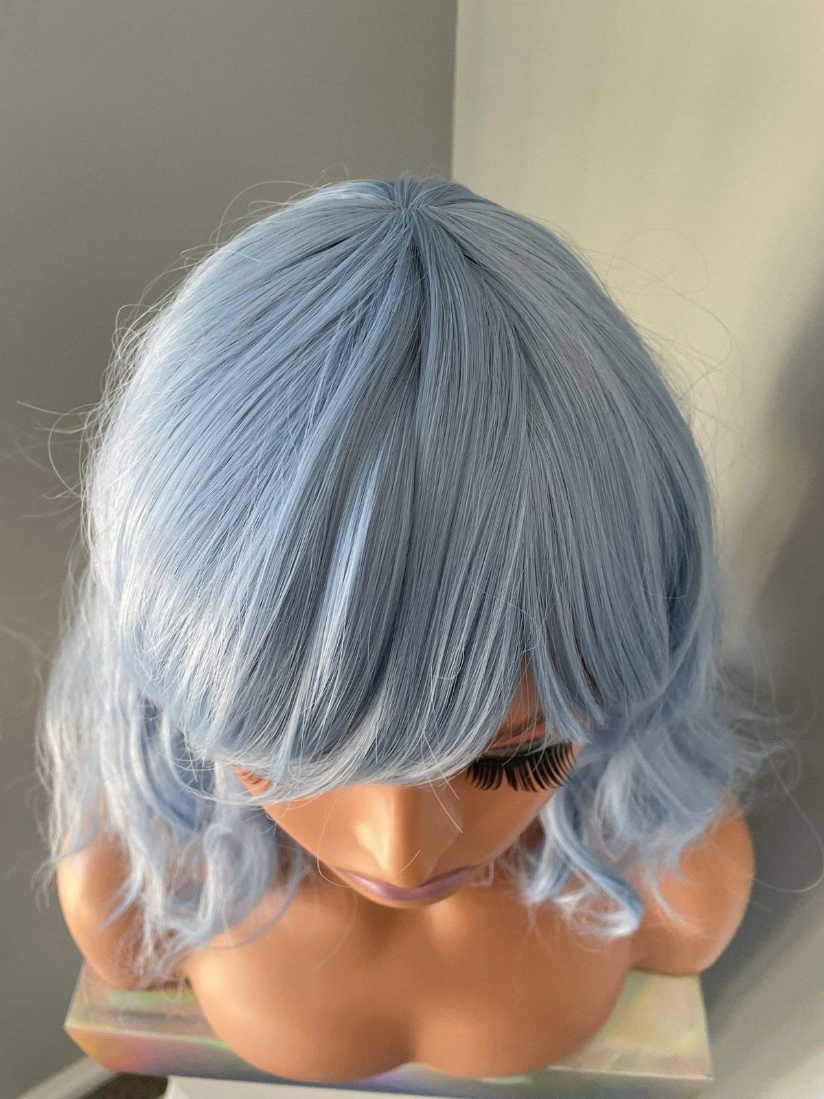 Faye Short Pastel Blue Body Wave Wig with Bangs displayed on a mannequin, showcasing soft waves and wispy bangs.
