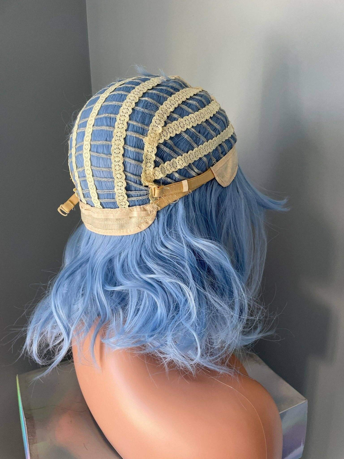 Back view of Faye Short Pastel Blue Body Wave Wig with Bangs showing cap construction and soft blue waves.
