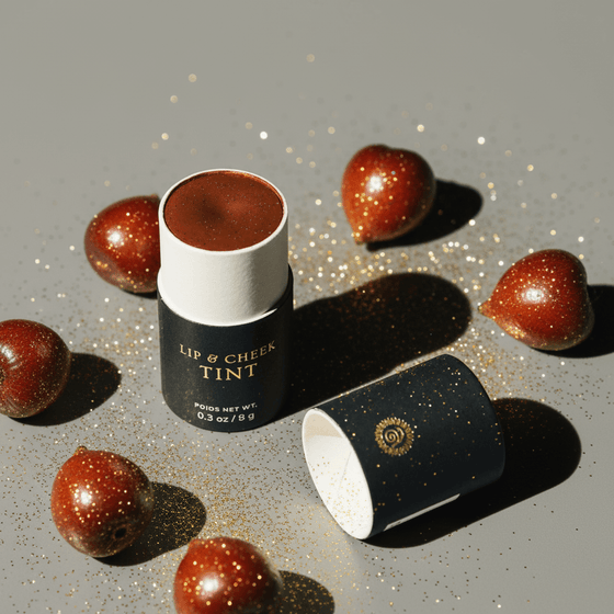 Lip and cheek tint with a black and white container on a gray background with fruits.