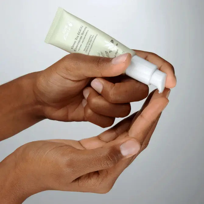 Hands applying Green Tea EGCG Concentrate Serum from a tube for daily antioxidant skincare.