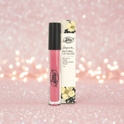 Pink lip gloss with black cap and floral packaging on a glittery pink background