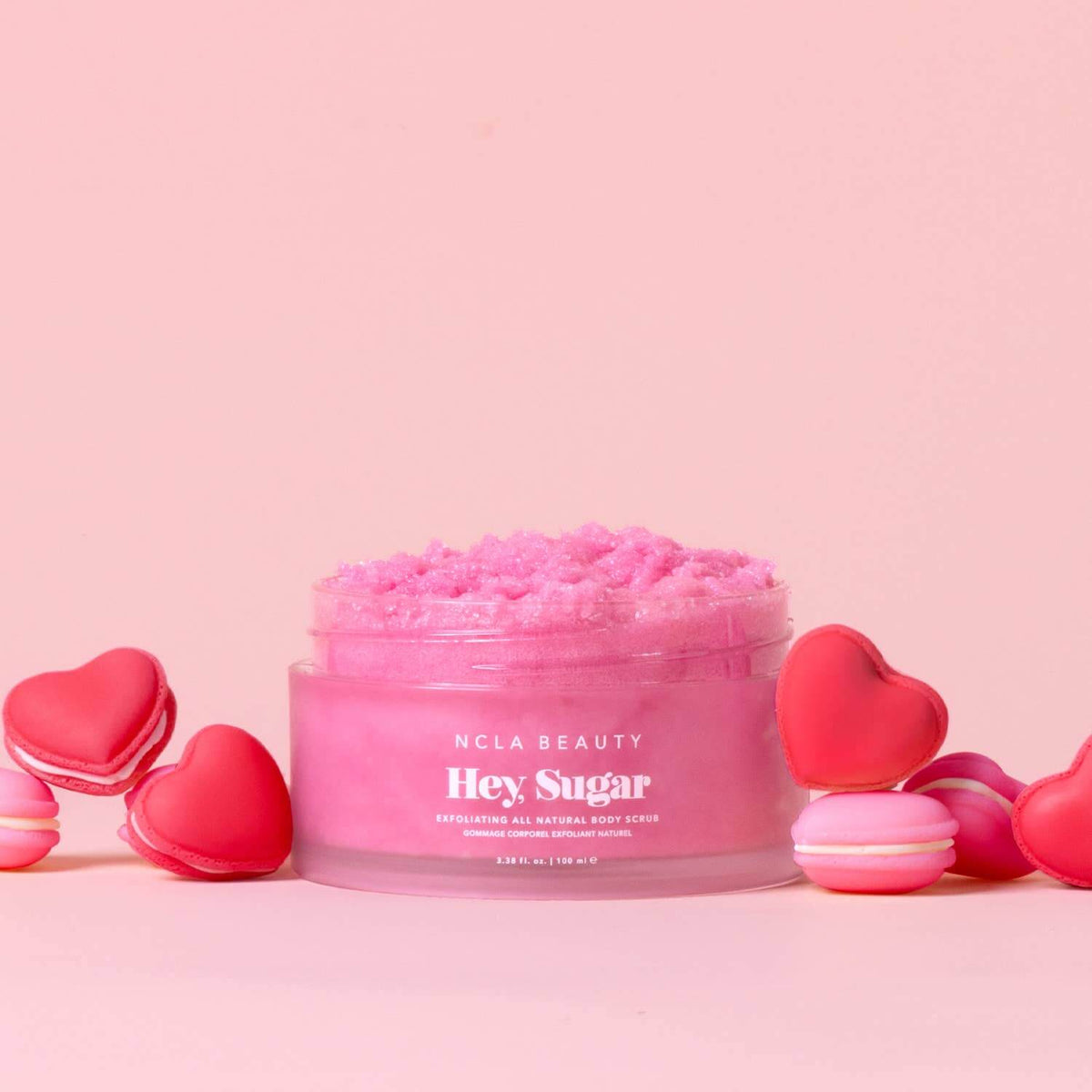 Pink body scrub jar with 'Hey Sugar' text on a pink background with heart-shaped containers.