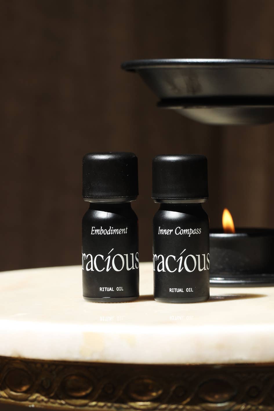 Bottles of Gracious ritual gel: Embodiment and Inner Compass grounding essential oil blend on a marble surface.