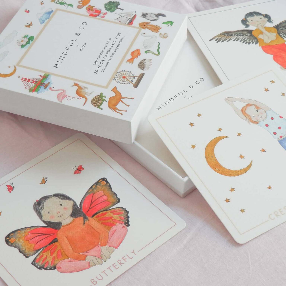 Set of illustrated cards with colorful designs on a pink surface, featuring the brand 'Mindful & Co'.