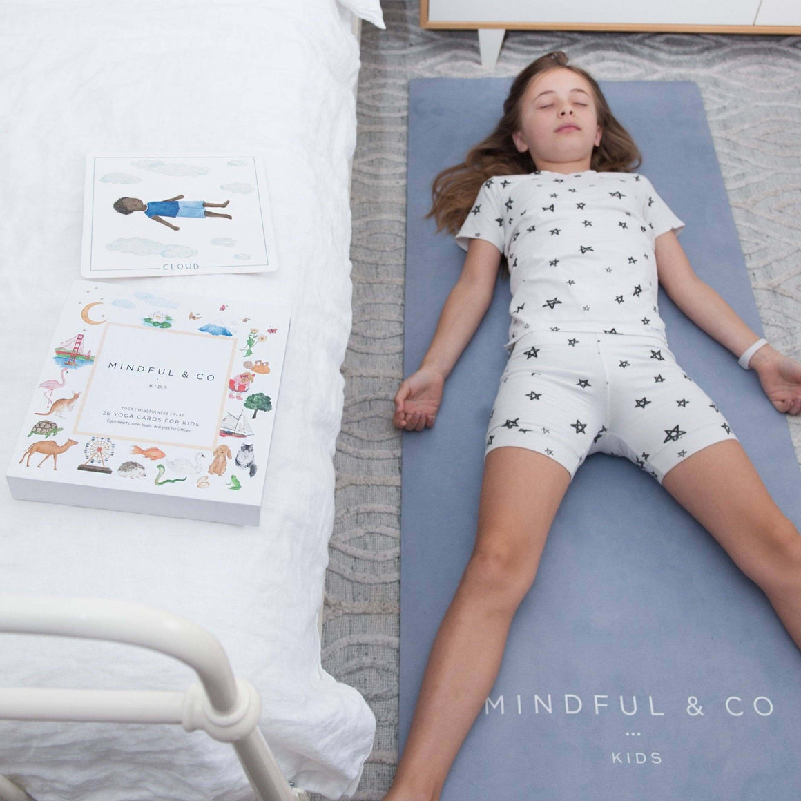 Child lying on a yoga mat with 'Mindful & Co' books nearby