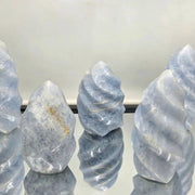 Group of blue calcite crystals on a reflective surface with a white background