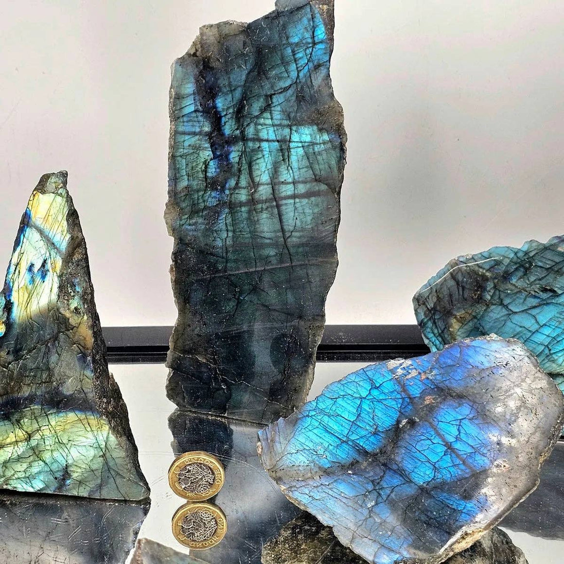Labradorite crystal with blue and green patterns on a reflective surface